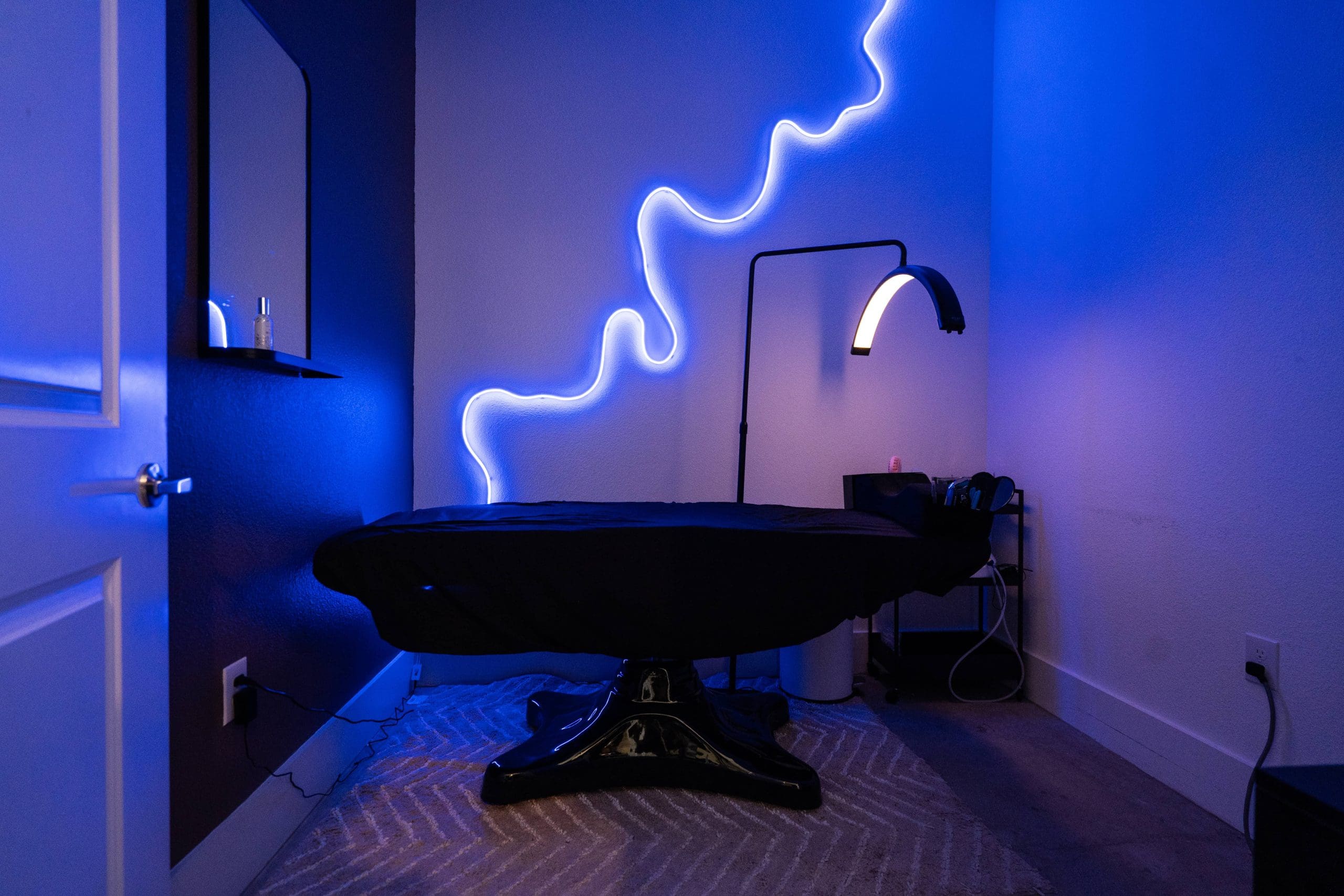 A treatment room lit blue, with a neon squiggle on the wall