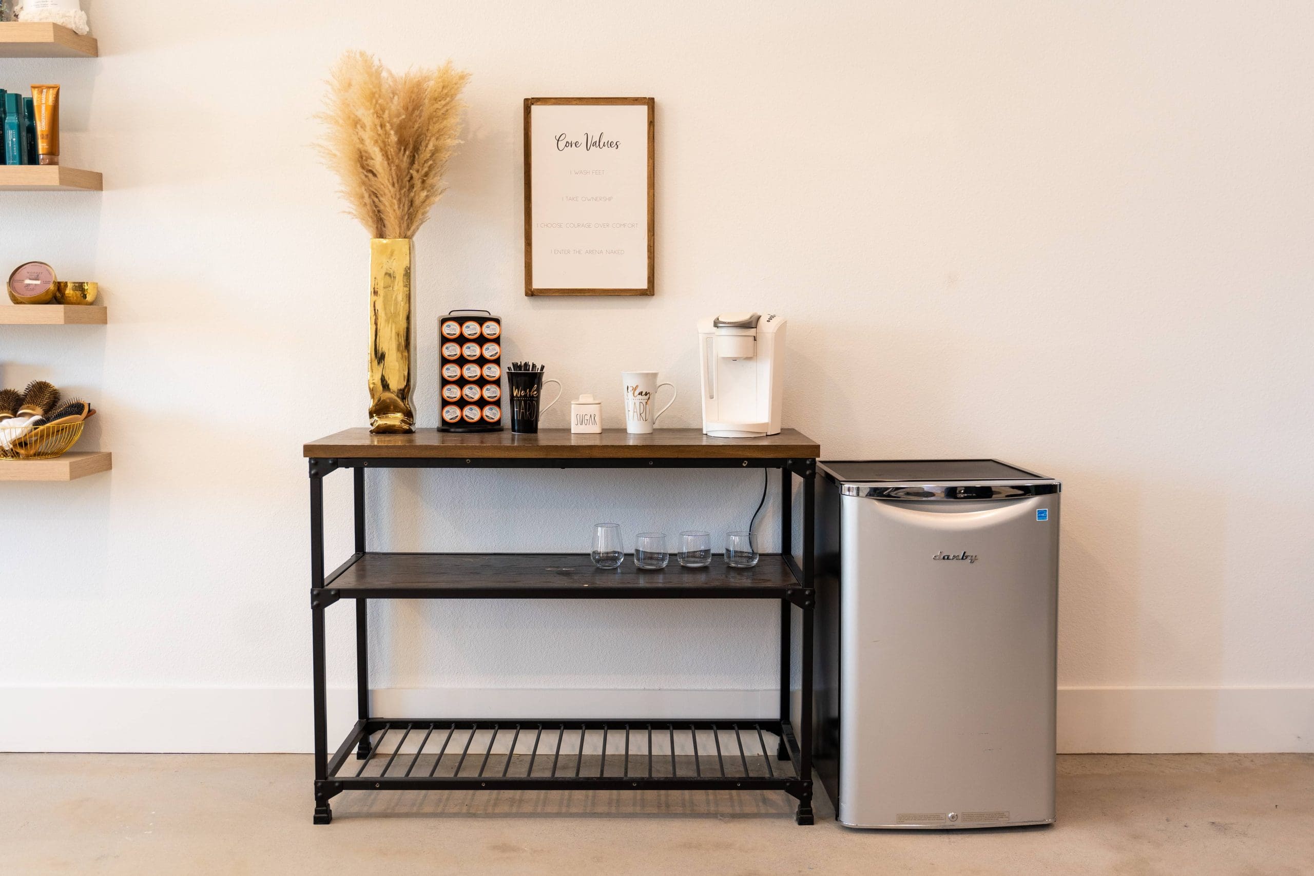 A refreshment station with a coffee maker beside dried pampas grass