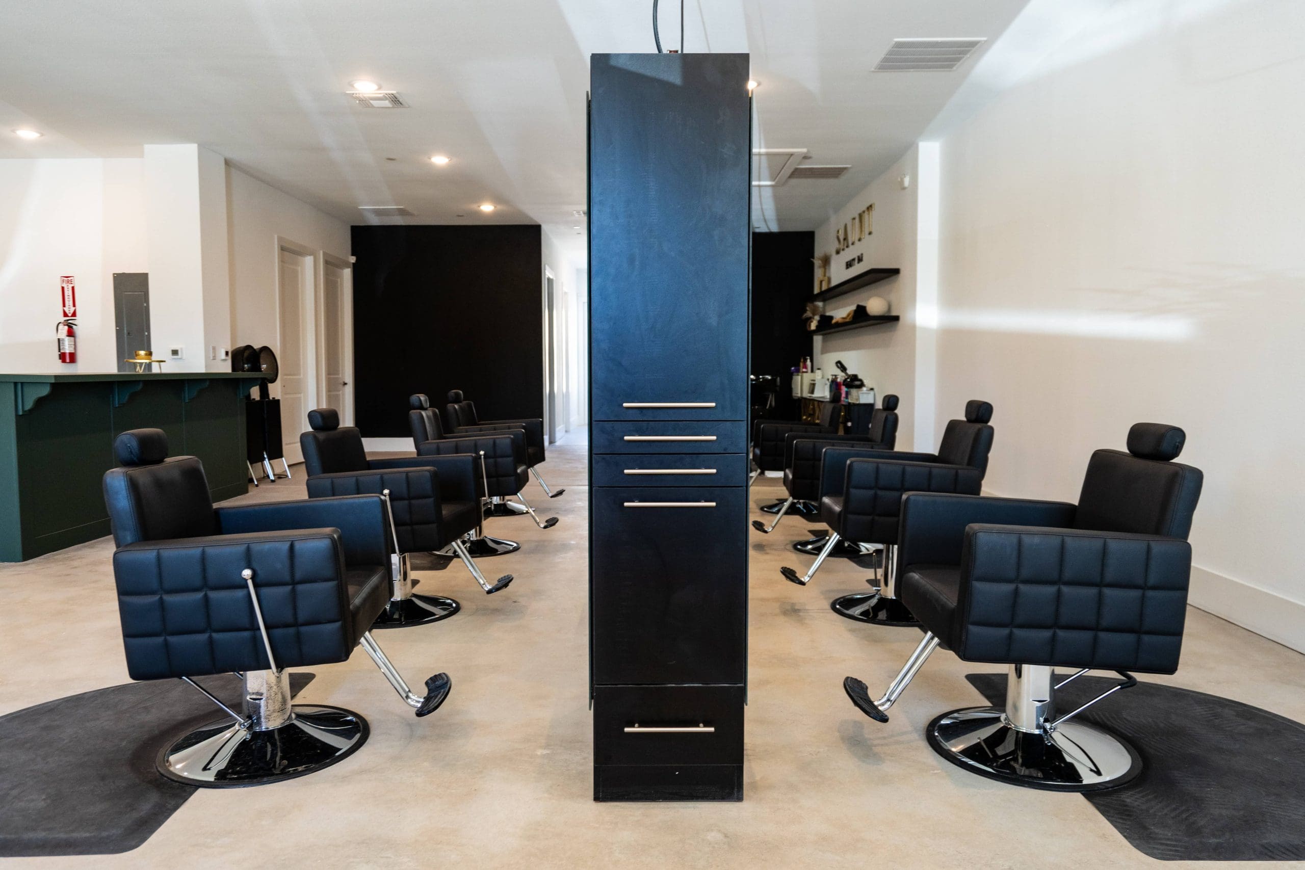 Rows of black styling chairs on either side of a central column